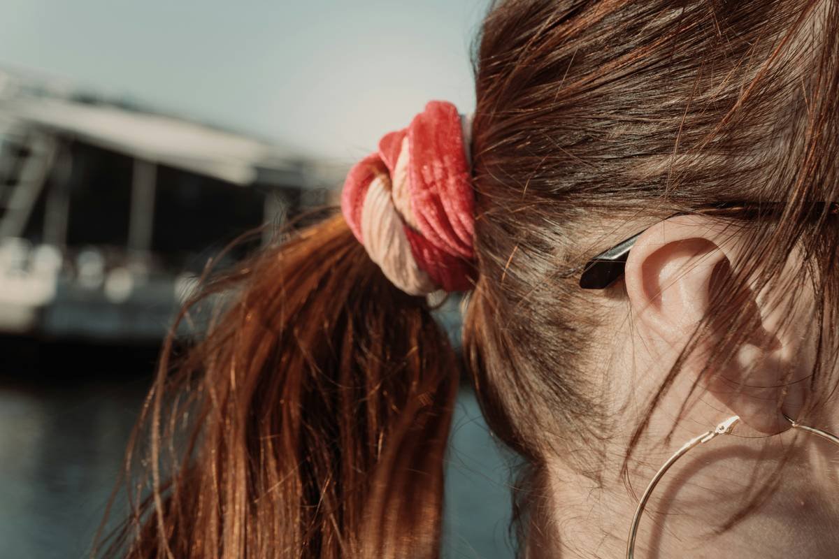 Close-up of hands using high-quality hair ties to style thick curly hair without causing dents or breakage